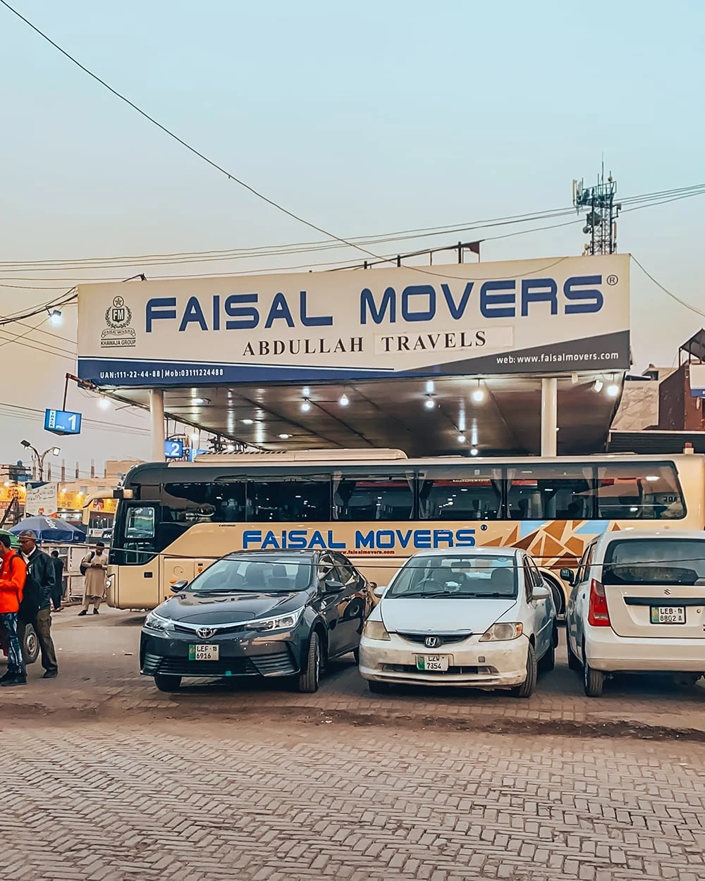The real Faisal Movers Lahore terminal building with green Faisal Movers buses